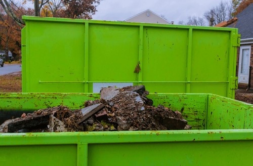 a green dumpster filled of soil waste from the yard